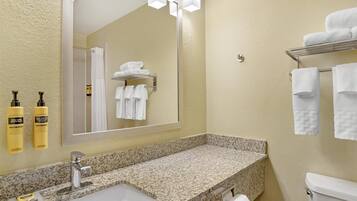 A bathroom with a granite countertop sink, a mirror, and a towel rack.