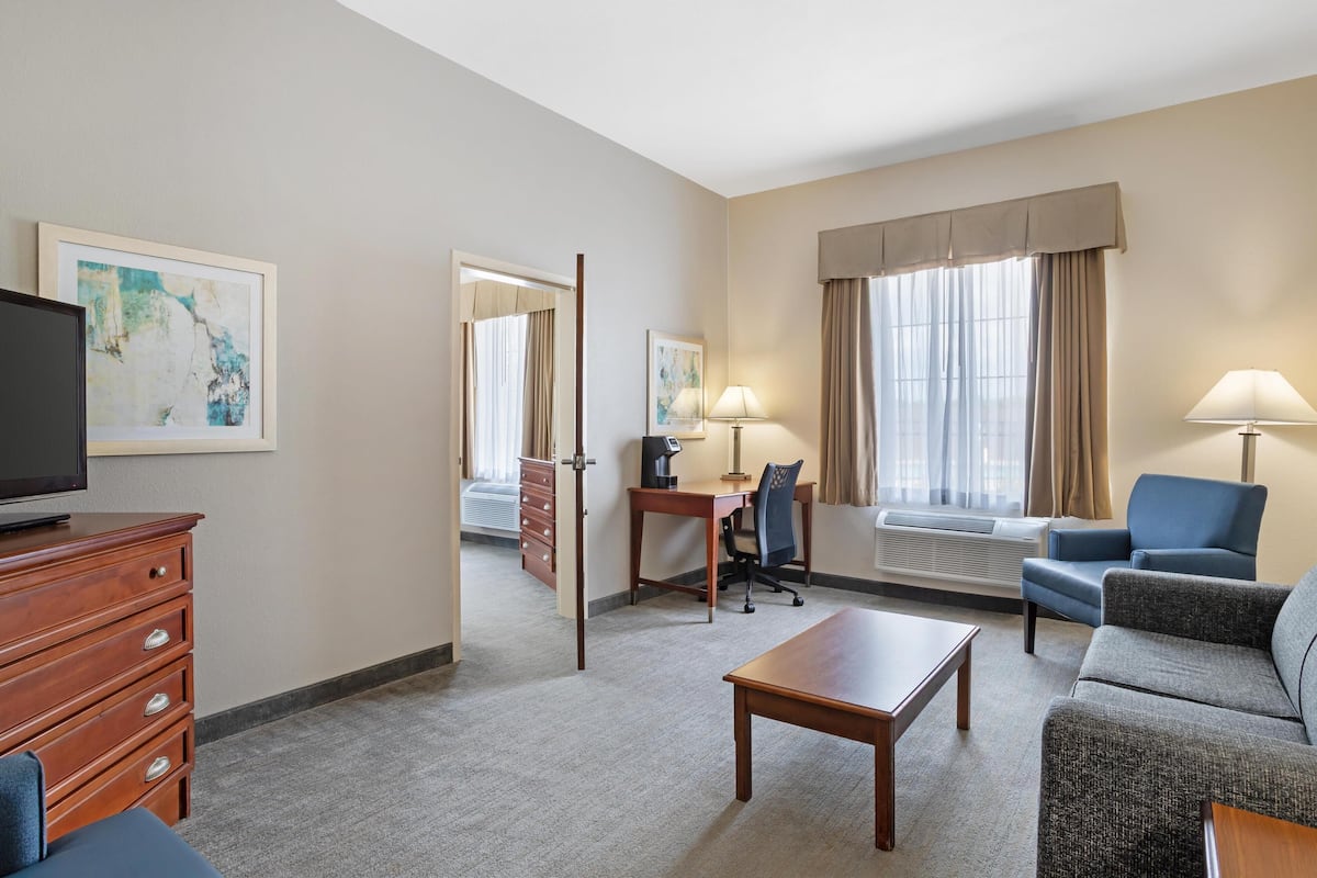 Een hotelkamer met een houten dressoir, een bureau met stoel, een bank, een salontafel en een televisie.