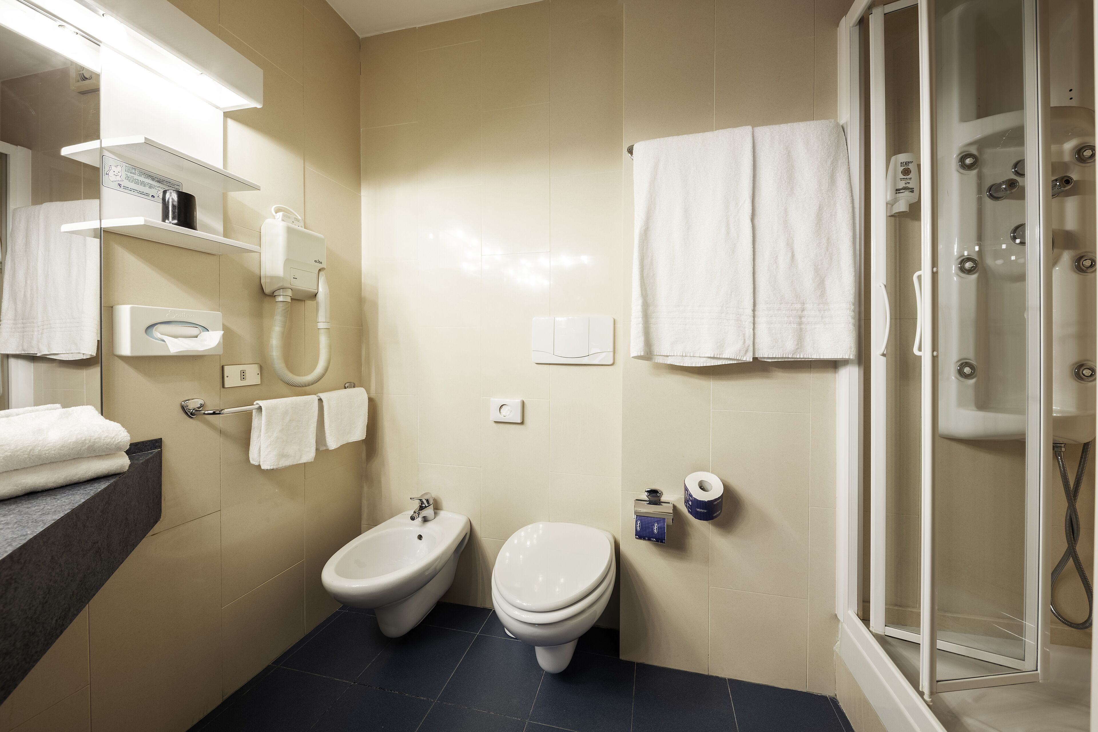 Une salle de bain équipée d’un bidet, de toilettes et d’une douche à parois de verre.