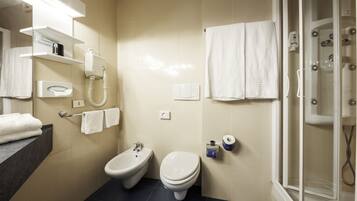 Une salle de bain équipée d’un bidet, de toilettes et d’une douche à parois de verre.