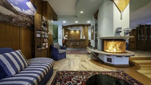 Un vaste espace de vie comprenant une cheminée, un canapé, une bibliothèque et un grand tapis.
