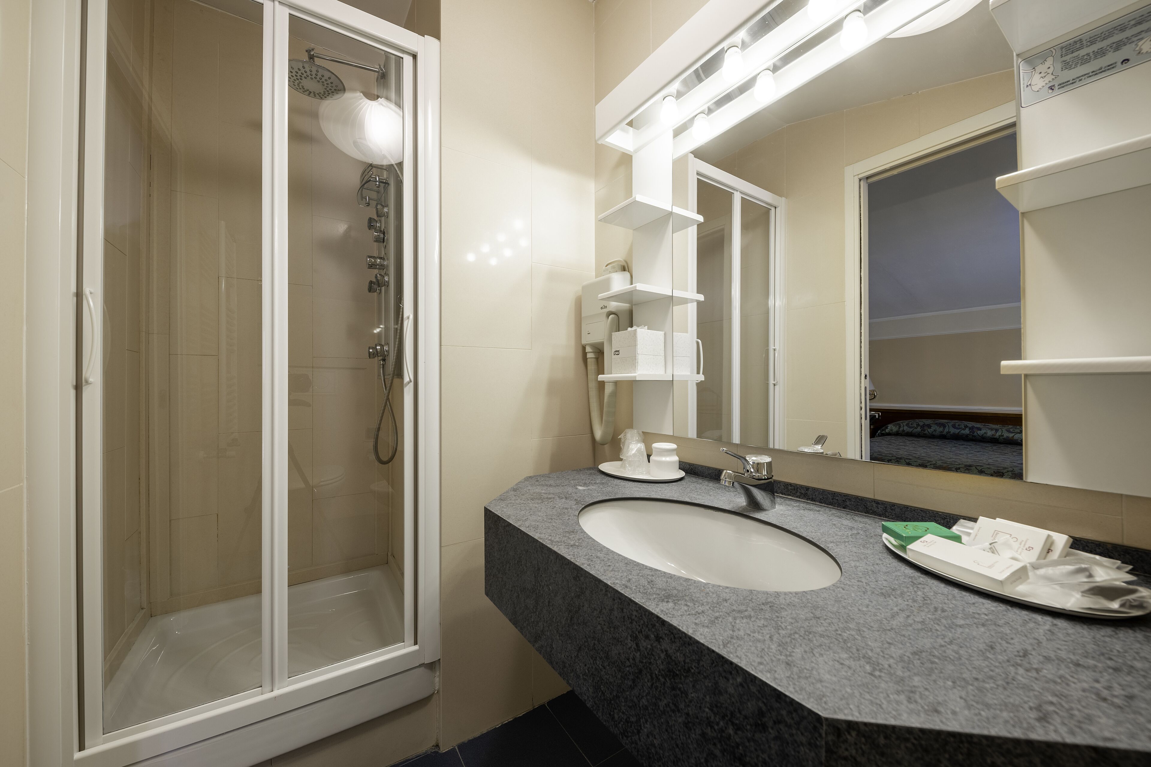 Un bagno con box doccia in vetro, un lavabo con specchio a parete e un porta asciugamani.