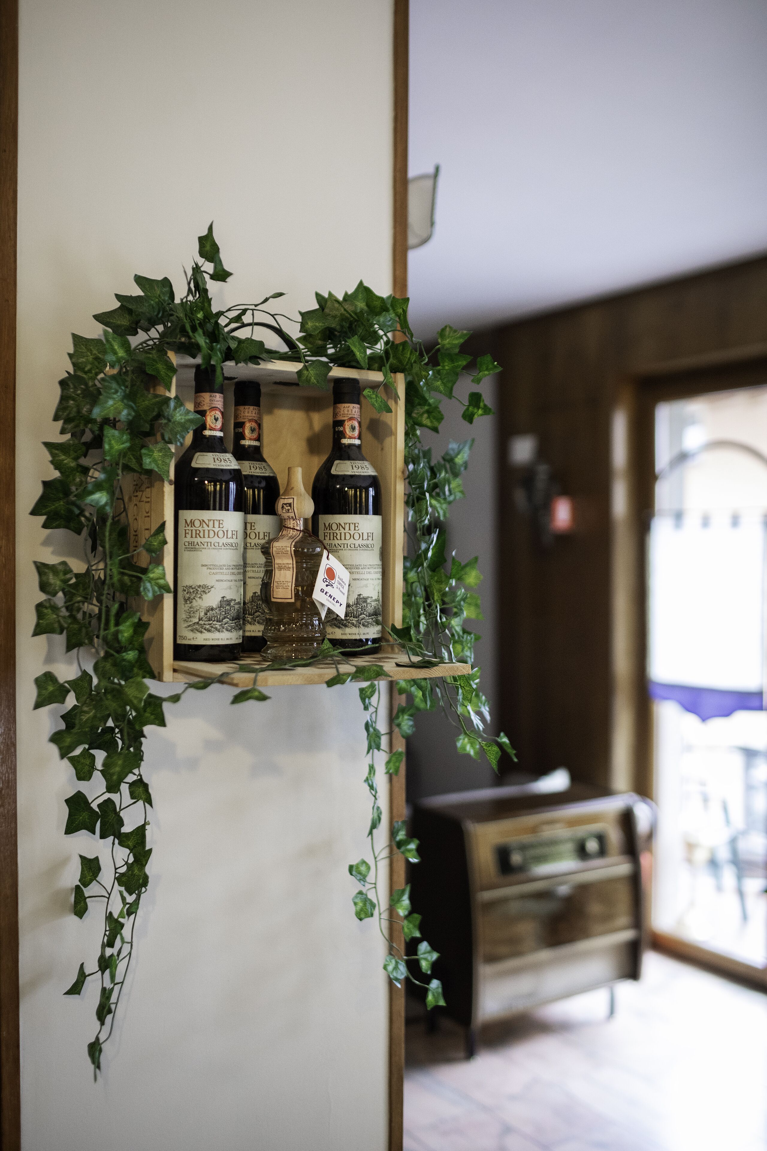 A display of Monte Firdolè wine bottles on a wooden shelf with ivy decorations.
