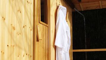 Ein Holzsaunaraum mit einem Handtuch an der Wand, einer Tür und einem Paar Hausschuhen auf dem Boden.