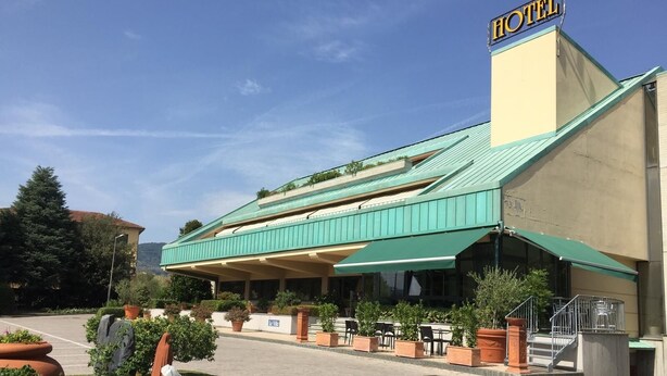 A hotel with a green roof, outdoor seating, and a staircase leading to the entrance. - Hotel Le Ville (Capannori)