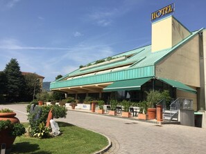 A hotel with a green roof, outdoor seating, and a staircase leading to the entrance. - Hotel Le Ville (Capannori)