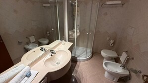 A modern bathroom with a large mirror, two sinks, a shower enclosure, and a toilet. - Hotel Le Ville (Capannori)