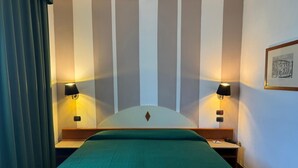 A hotel room with a bed, two bedside lamps, a headboard, and a framed picture on the wall. - Hotel Le Ville (Capannori)