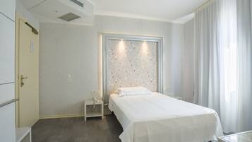 Una habitación de hotel con una cama, una mesita de noche, una pequeña mesa y una ventana con cortinas.