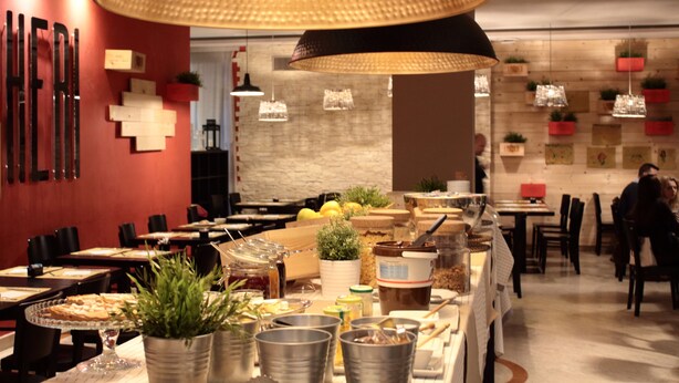 Un restaurante con varias mesas, diversos platos y lámparas colgantes.
