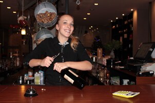 A bar area with a bartender pouring a drink, a cash register, and a cash register drawer.
