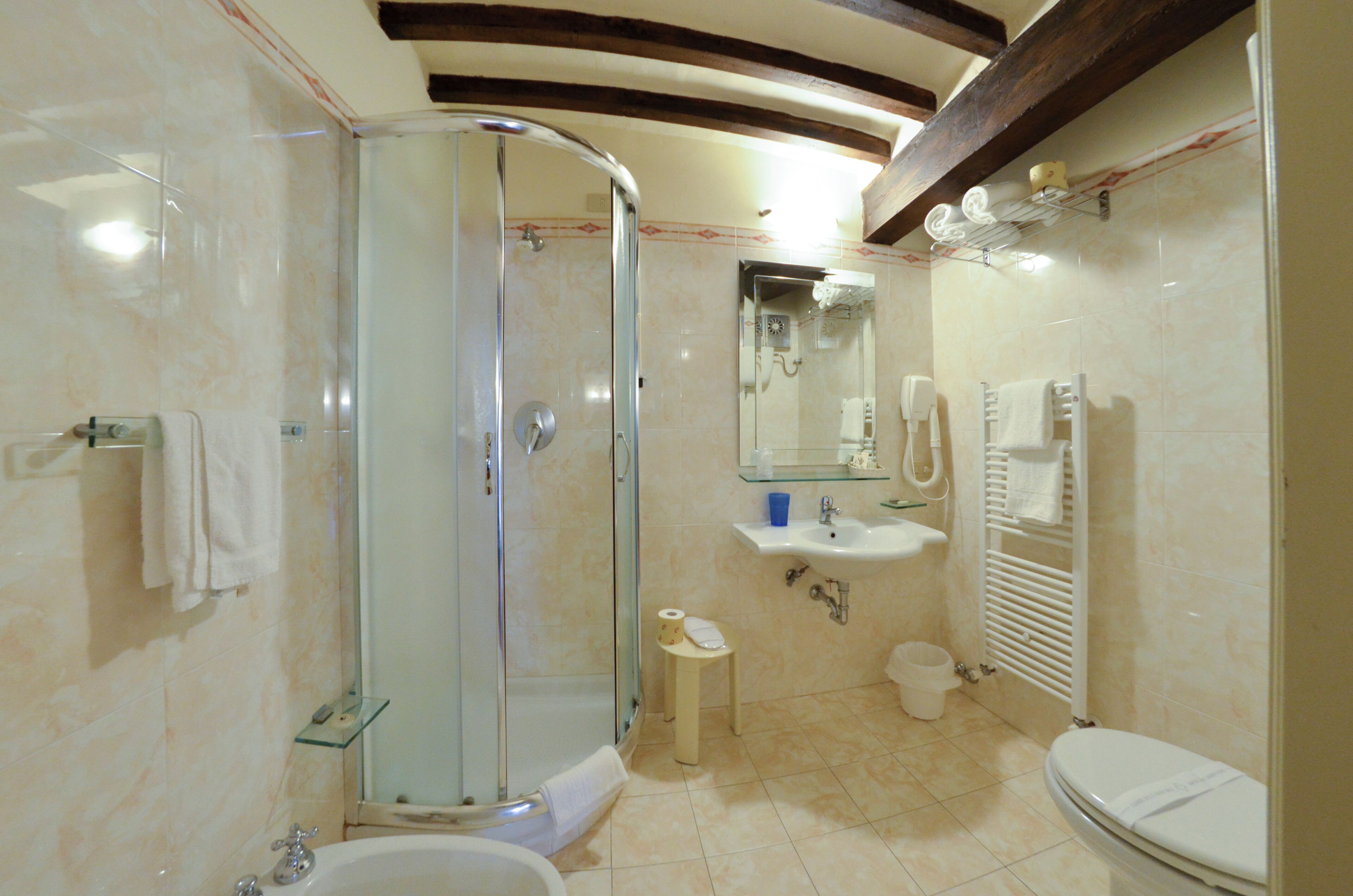 A modern bathroom with a glass-enclosed shower, a sink with a mirror, a toilet, and a small trash bin.