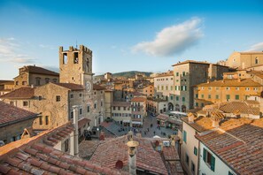 A historic town square with stone buildings, a prominent tower, and a clear sky. - Hotel San Michele (Cortona)