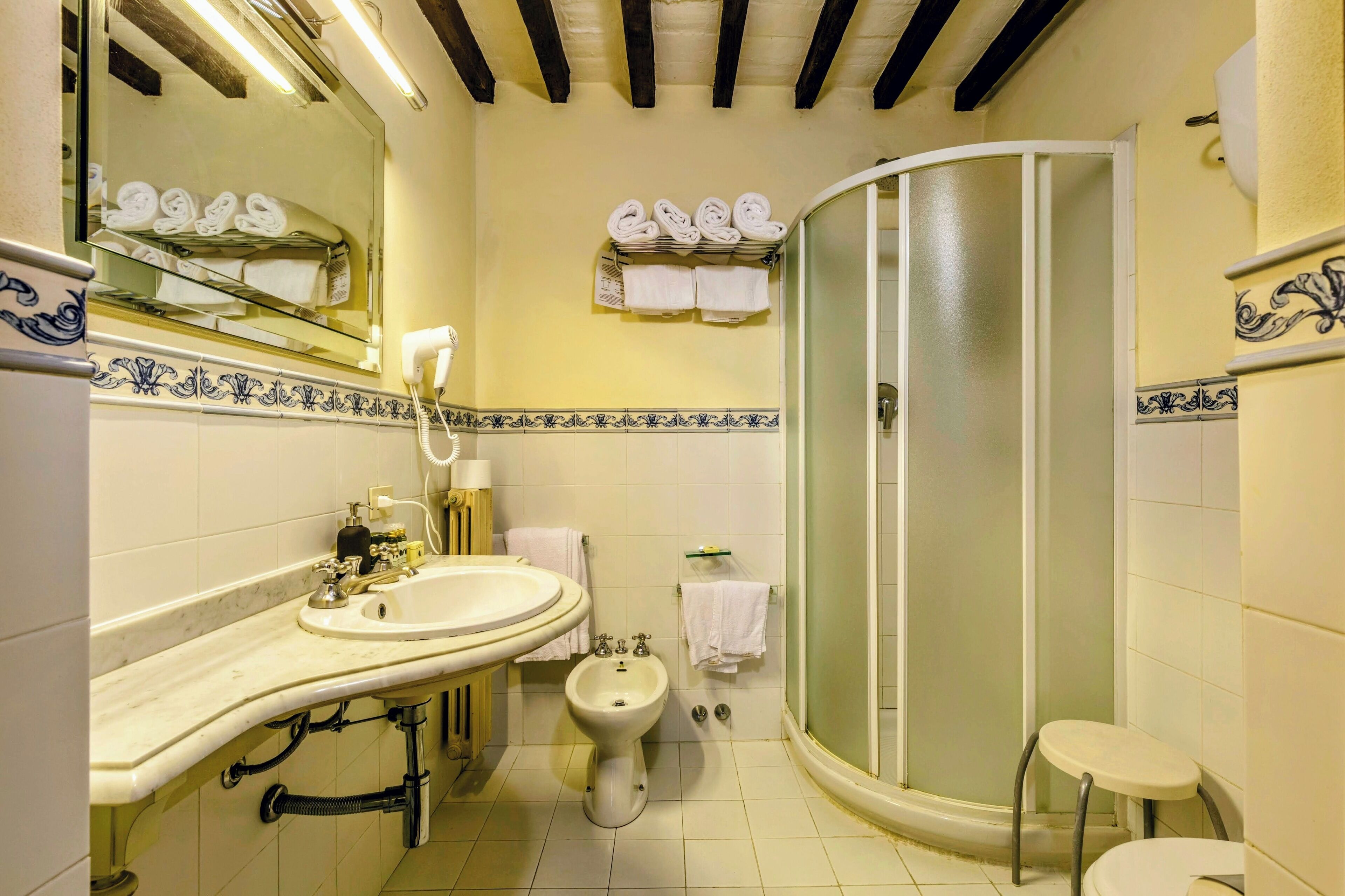 A bathroom with a sink, bidet, and a glass-enclosed shower.