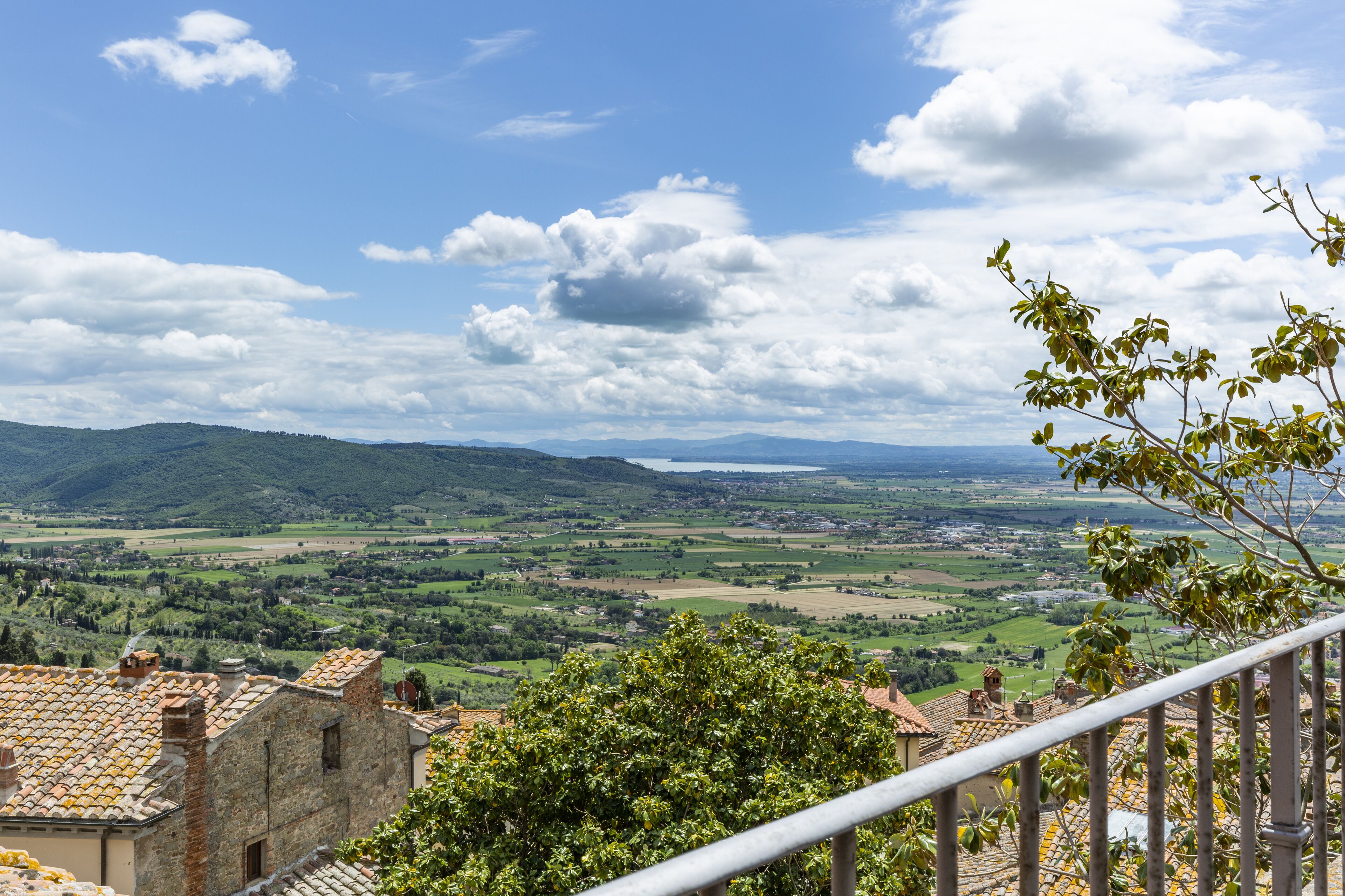 A view of a rural landscape with a distant body of water, rolling hills, and a clear sky.