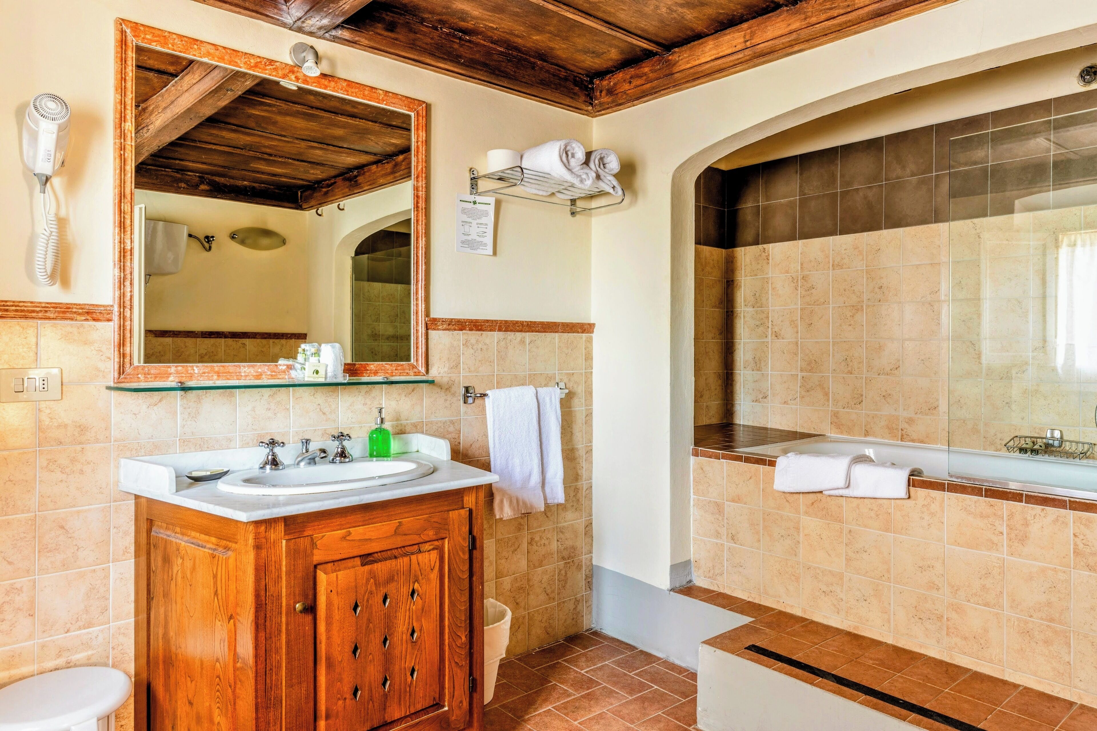 A bathroom with a wooden vanity, a large mirror, a shower area, and a towel rack.