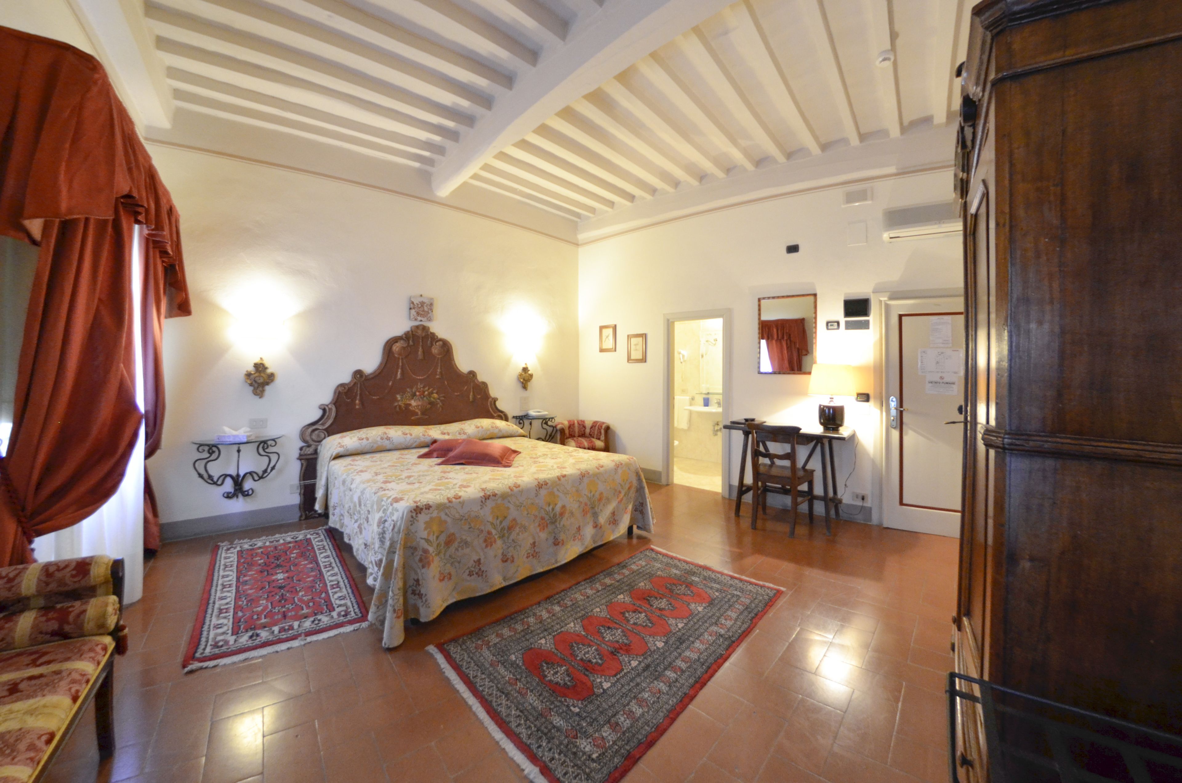 A bedroom with a large bed, two bedside tables, a desk, and a chair.