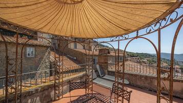Una terraza en la azotea con una mesa y sillas de metal, un parasol grande y vistas de la ciudad.