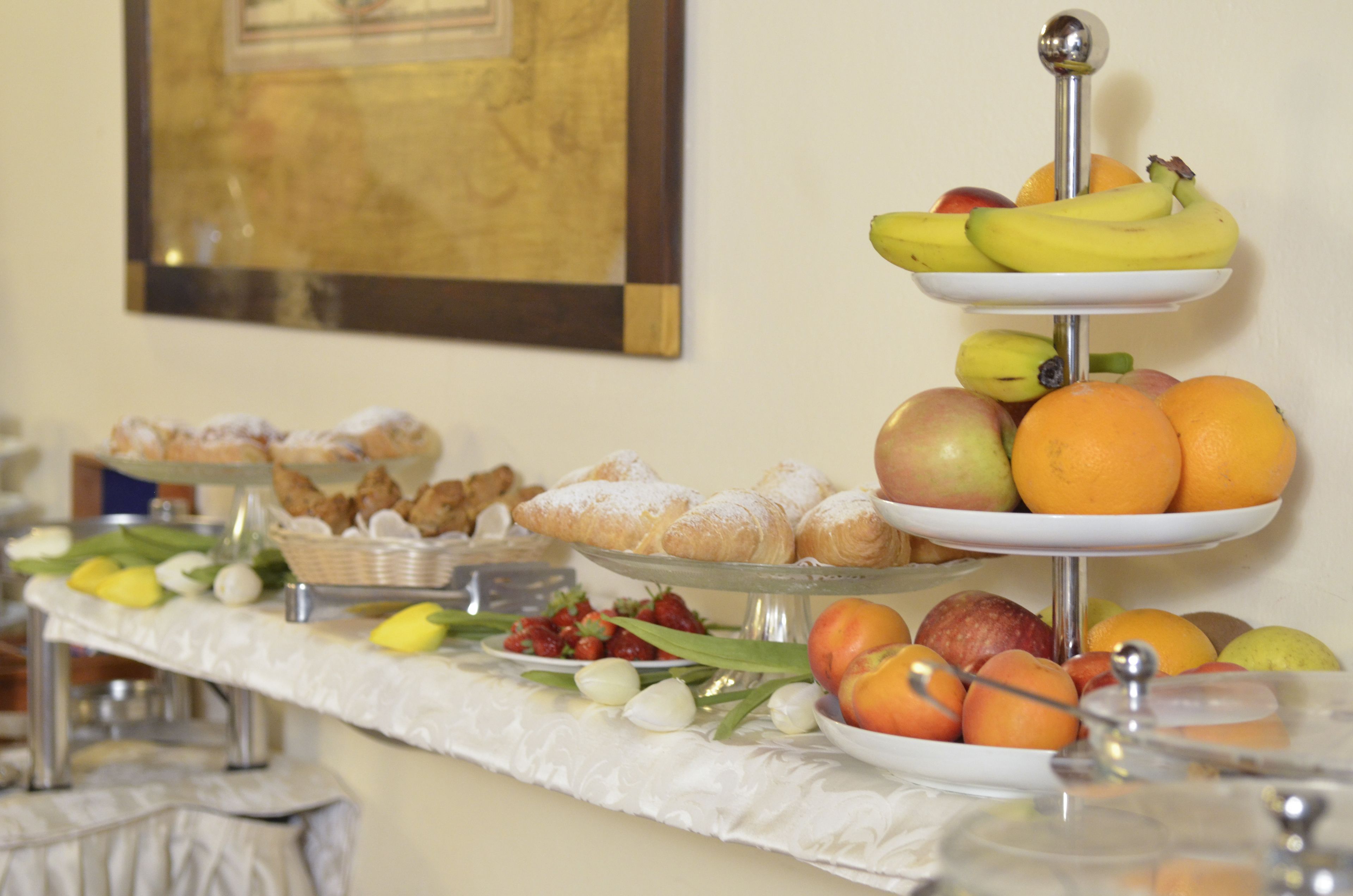 A buffet with various food items including pastries, fruits, and bread.
