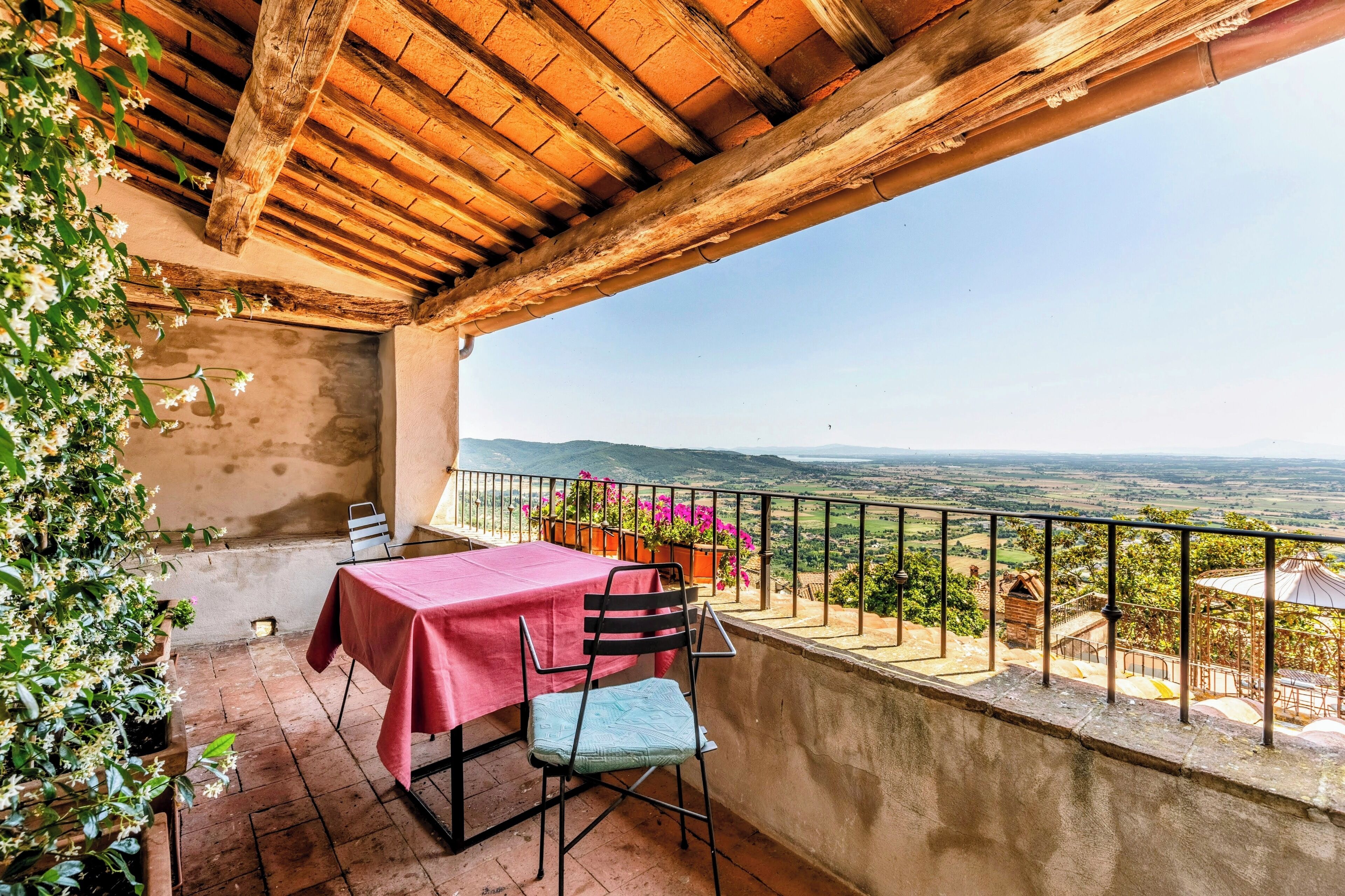 A terrace with a table and chair, overlooking a scenic landscape.