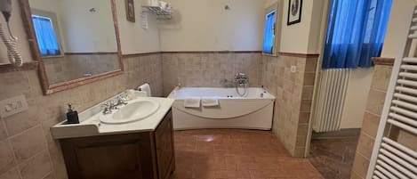A bathroom with a sink, mirror, vanity, bathtub, and a toilet.