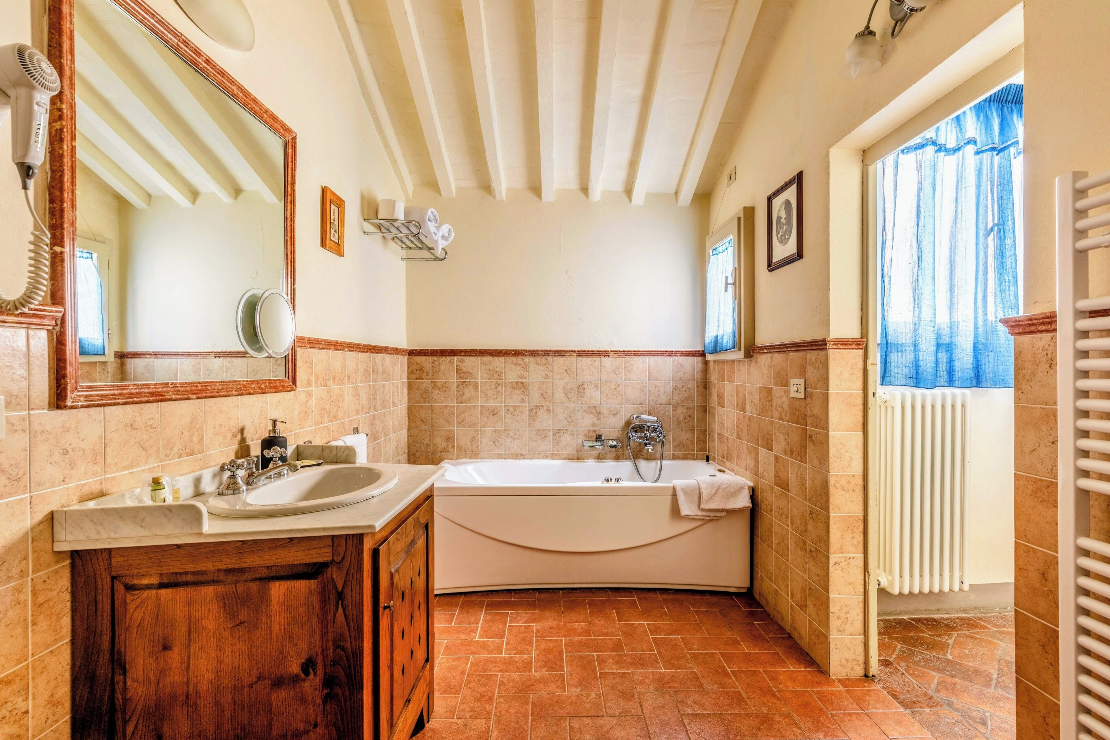 A bathroom with a double sink vanity, a bathtub, and a large mirror.