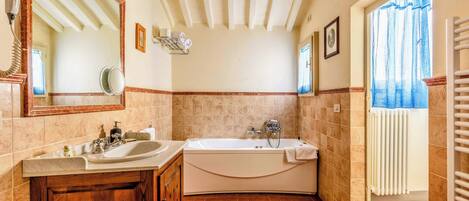 A bathroom with a double sink vanity, a bathtub, and a large mirror.