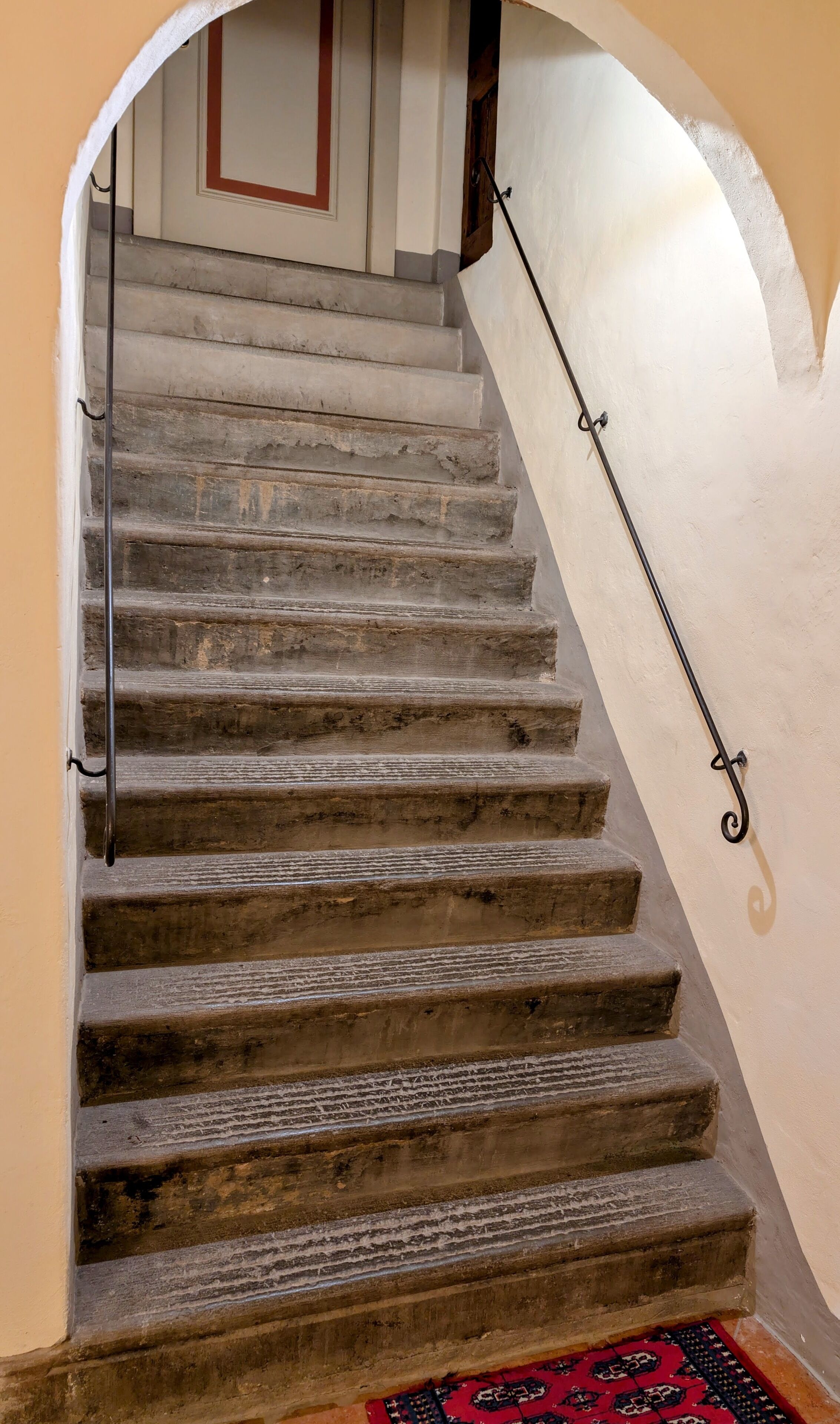 A stone staircase with a handrail, leading to a landing with a door.
