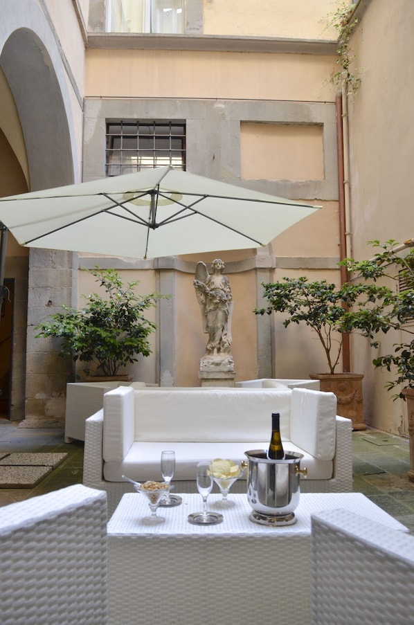 An outdoor seating area with a white table set for two, a statue, and potted plants. - Hotel San Michele (Cortona)
