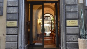A hotel entrance with an arched doorway, stone facade, and a sign indicating the name 'Albergo I Michele'. - Hotel San Michele (Cortona)