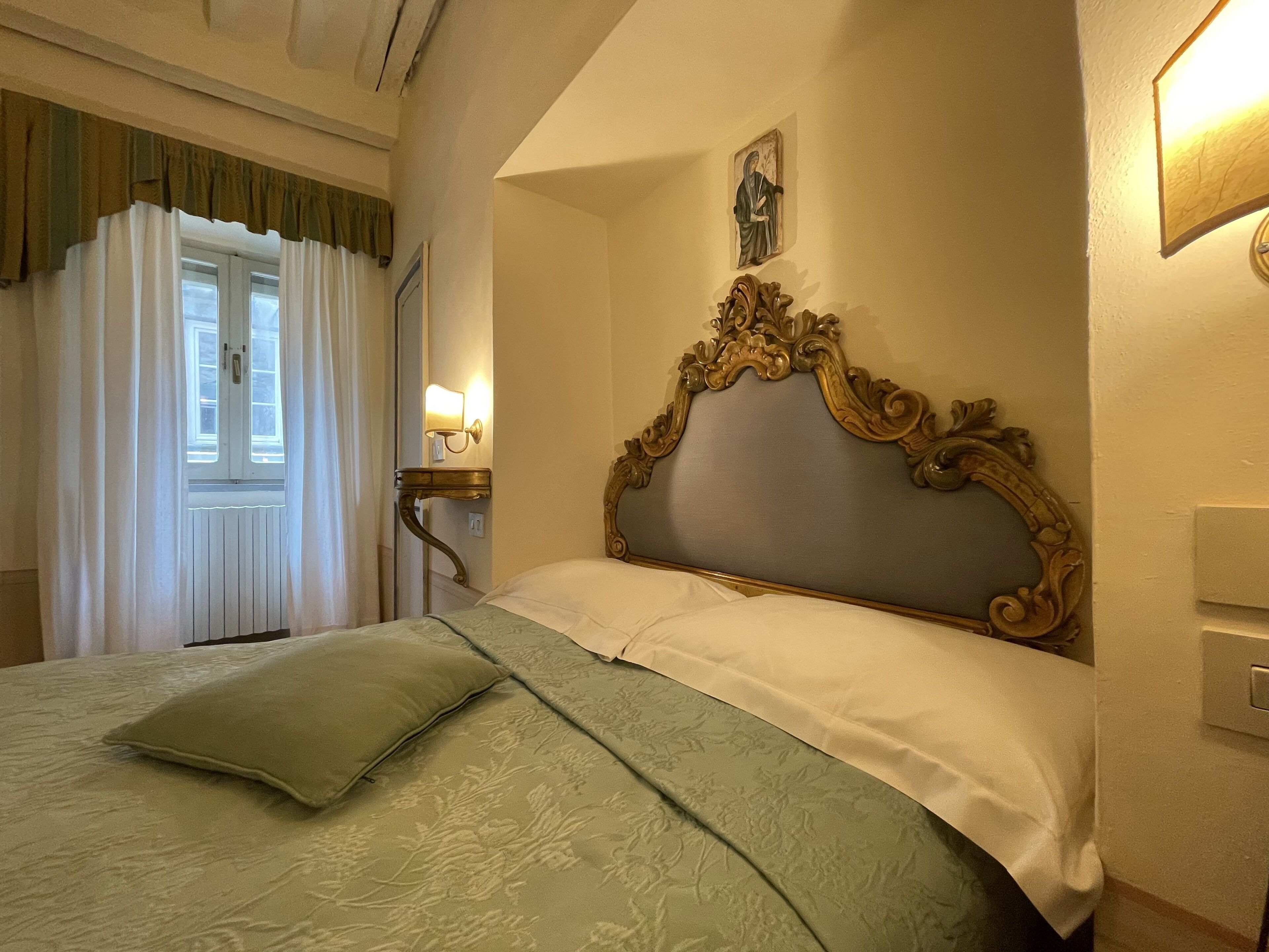 A neatly made bed with a floral-patterned bedspread and a single green pillow.