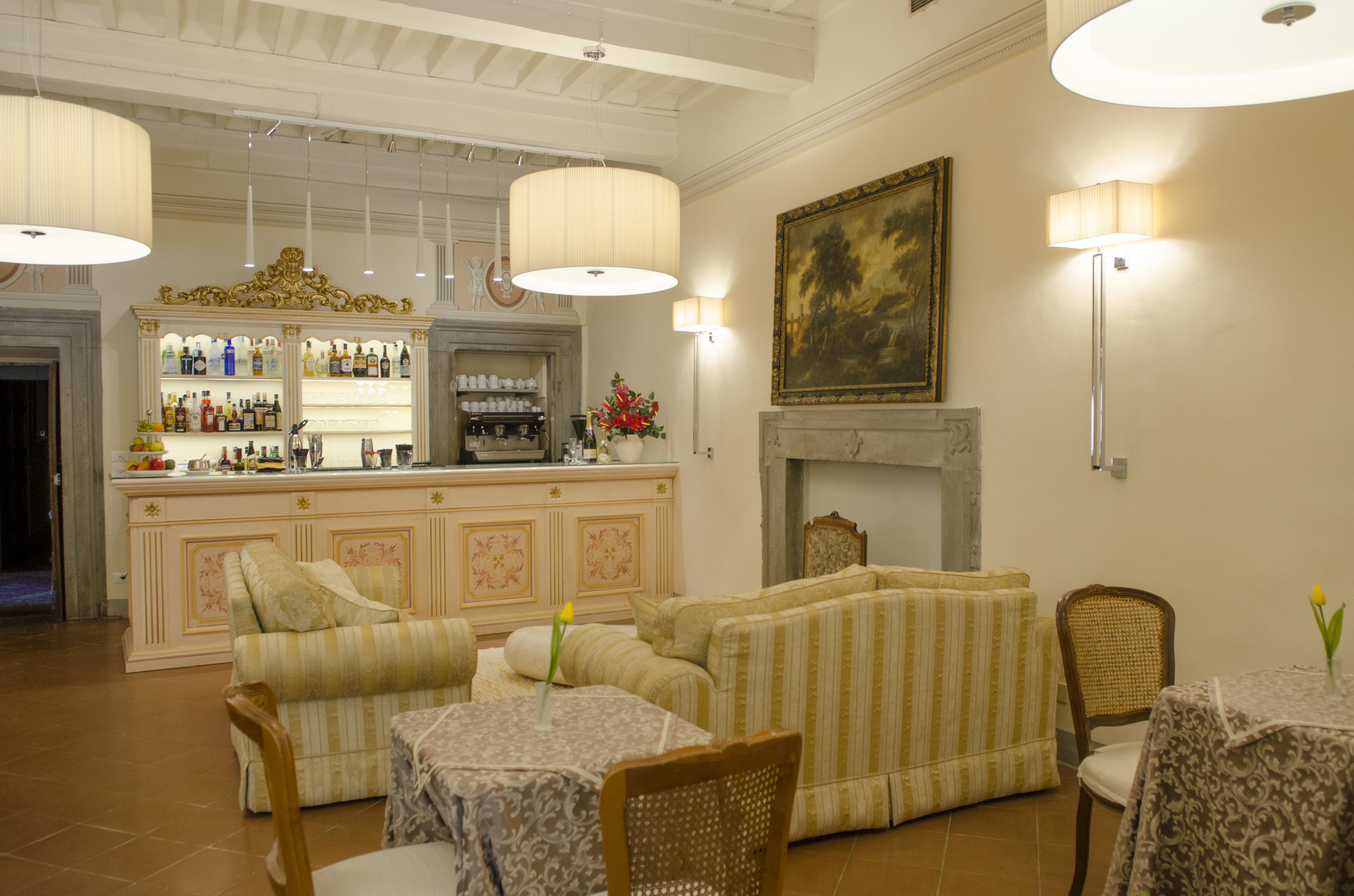 A bar area with a counter and shelves of bottles, a fireplace, and seating with tables.