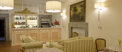 A bar area with a counter and shelves of bottles, a fireplace, and seating with tables.