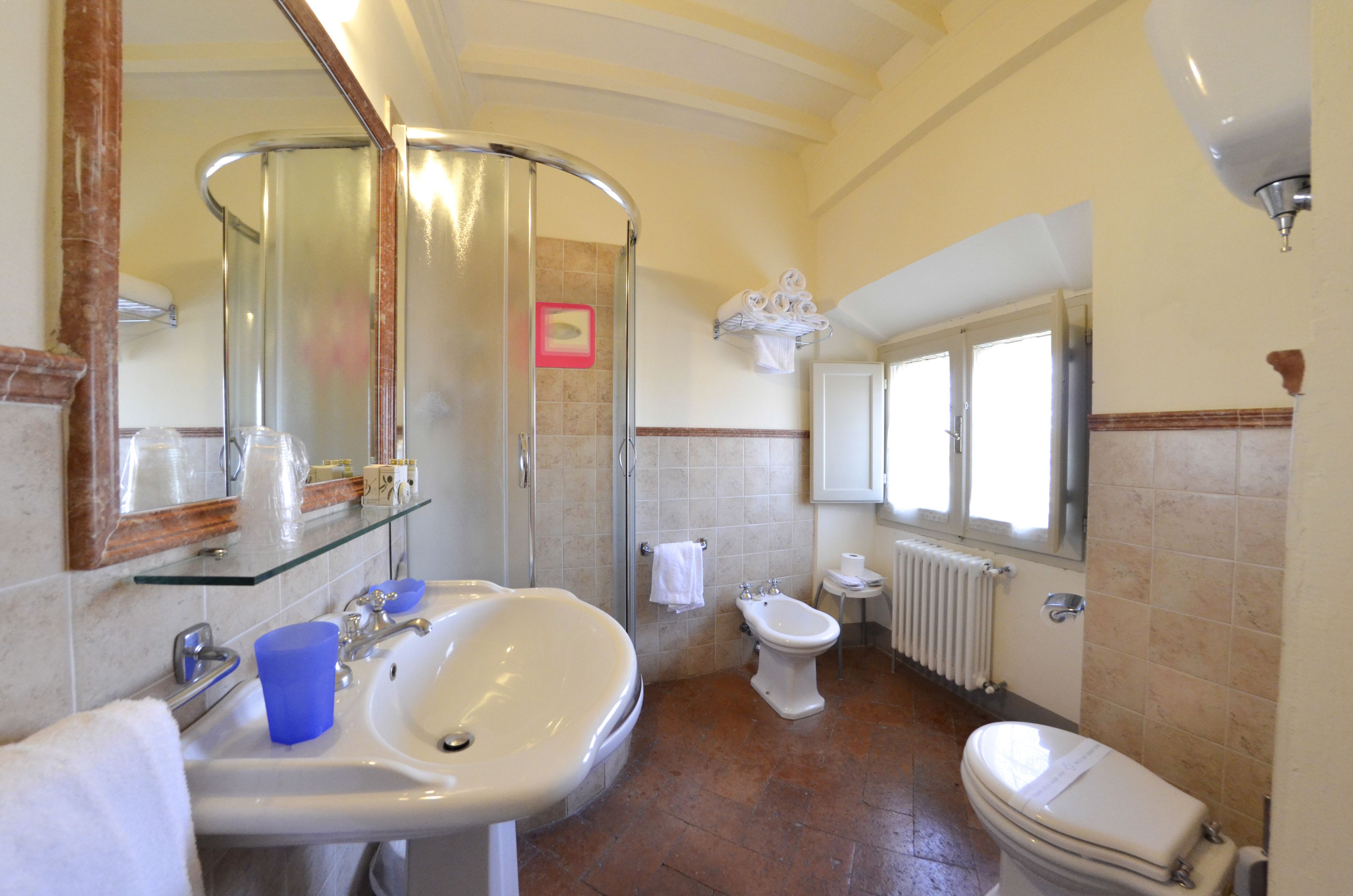 A bathroom with a glass shower enclosure, a sink, a bidet, and a toilet.