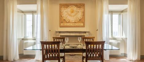 Comedor con mesa de vidrio, sillas de madera y un reloj de pared grande.
