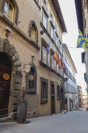 A historic building with a large potted plant, a sign for 'Hotel Michele', and multiple flags. - Hotel San Michele (Cortona)