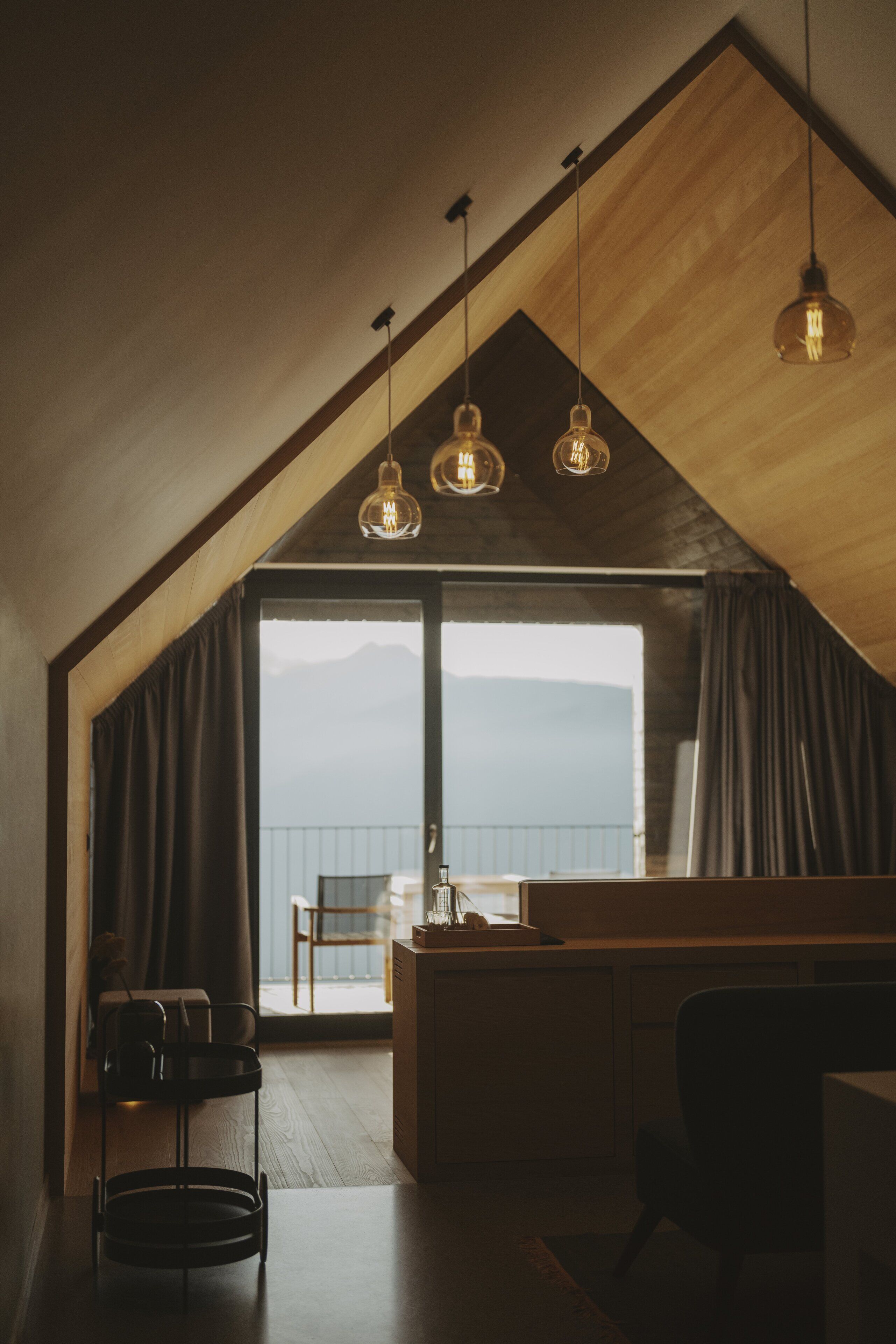 Eine moderne Küche mit Holzbalkendecke, einer Bar und Bergblick durch große Fenster.