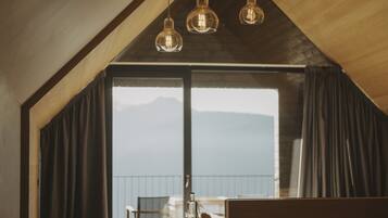 Eine moderne Küche mit Holzbalkendecke, einer Bar und Bergblick durch große Fenster.