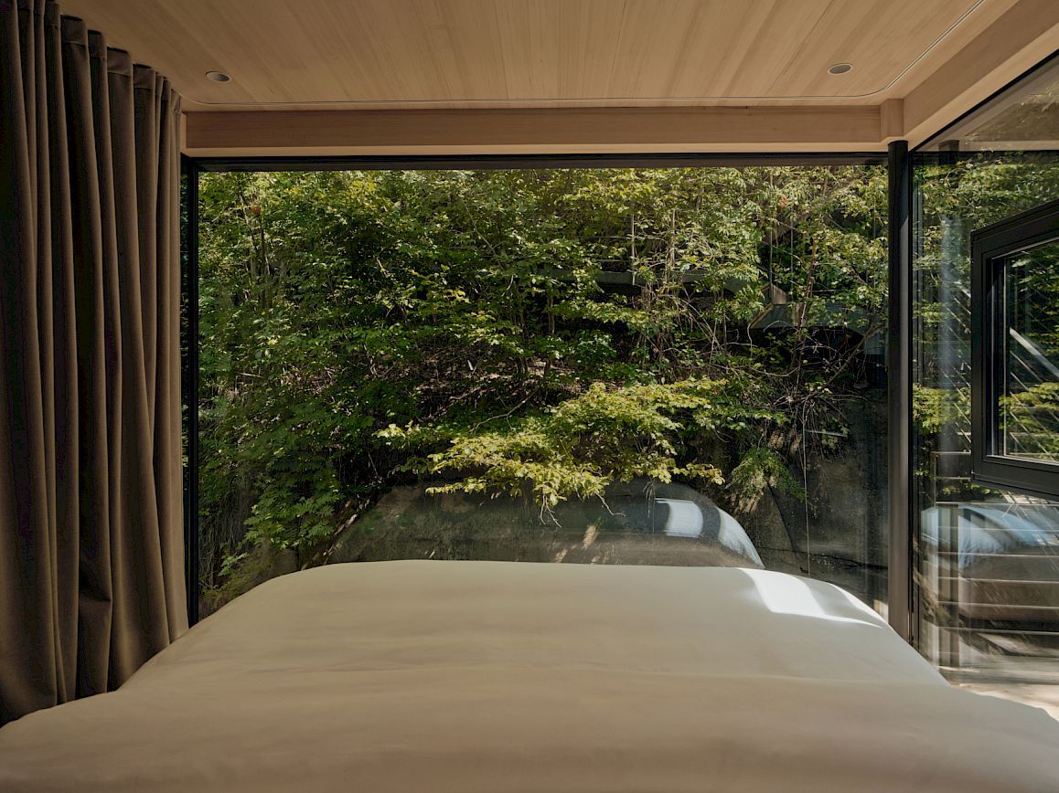 Un dormitorio con una ventana grande, una cama y cortinas.