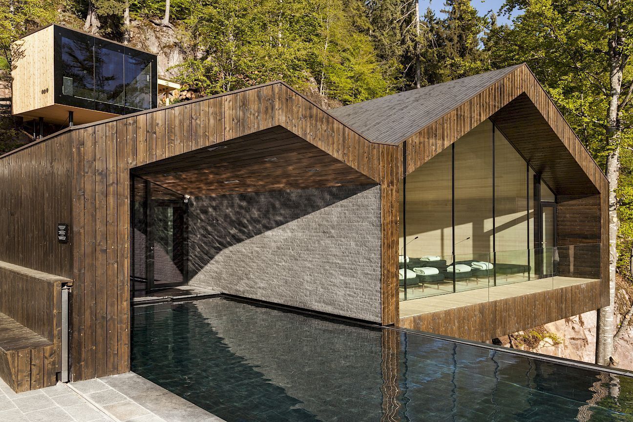 A modern building with a pool, wooden exterior, and large windows.