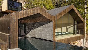 A modern building with a pool, wooden exterior, and large windows.