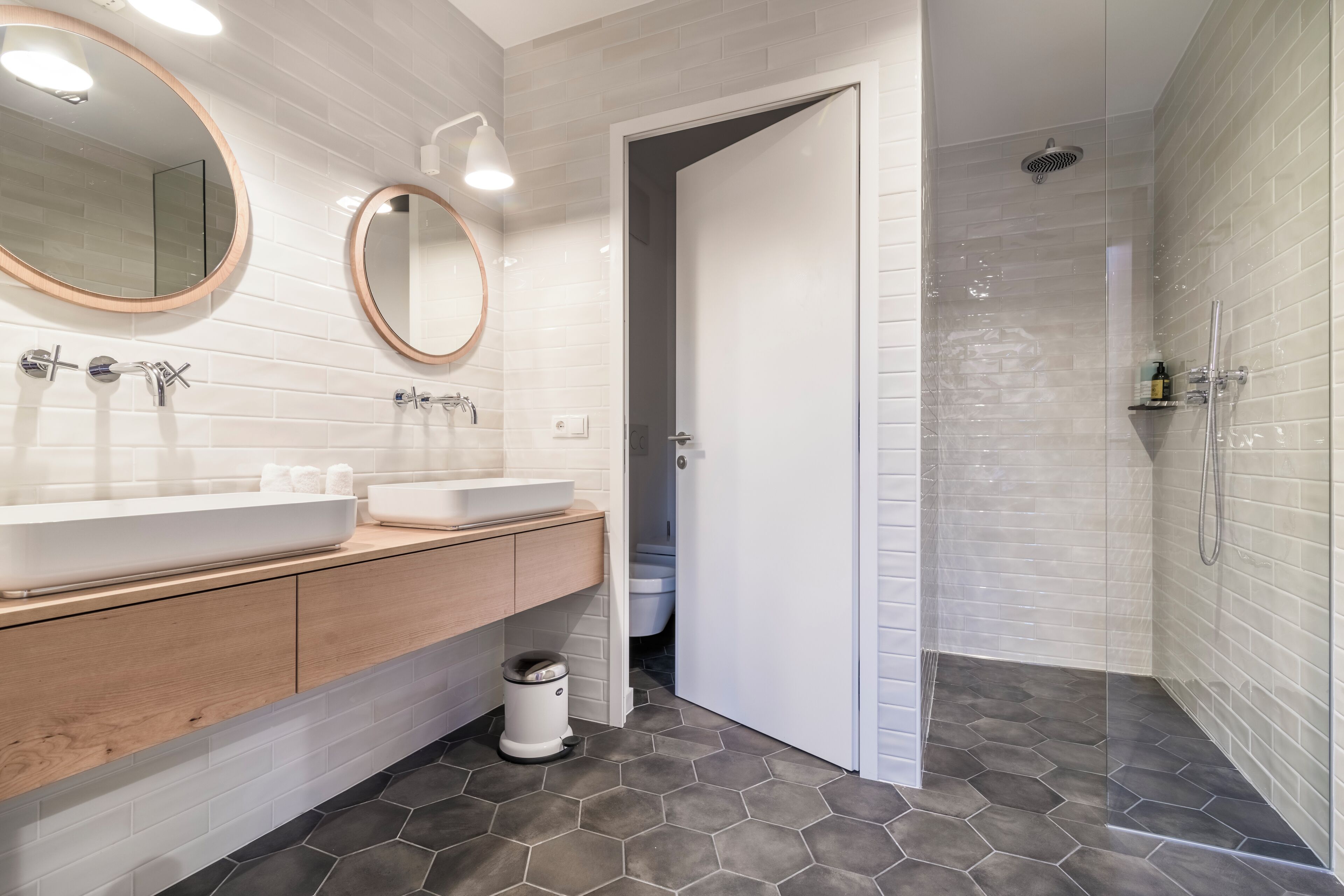 A modern bathroom with two sinks, a mirror, and a shower area.