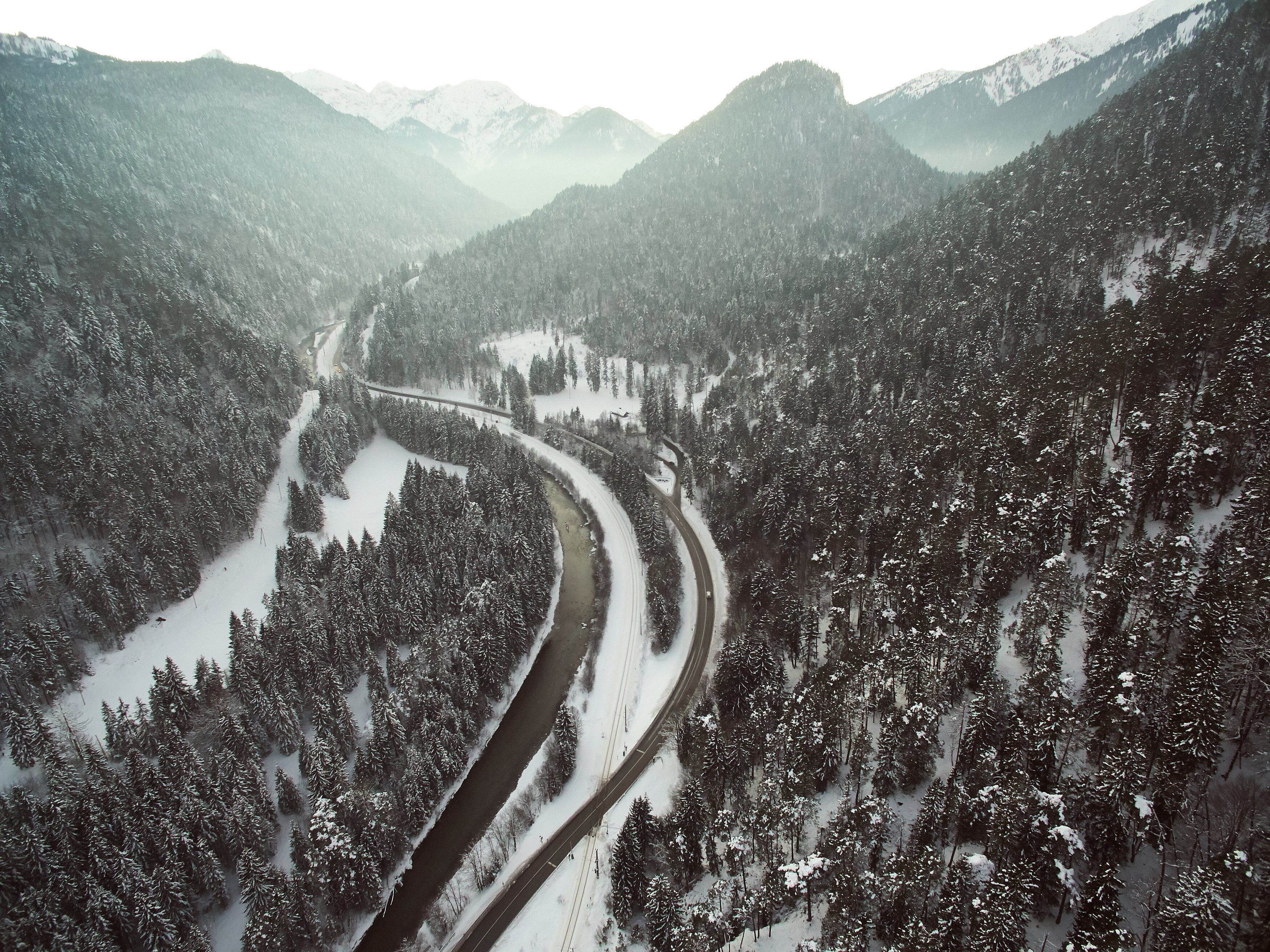 Un paisaje montañoso cubierto de nieve con una carretera serpenteante.