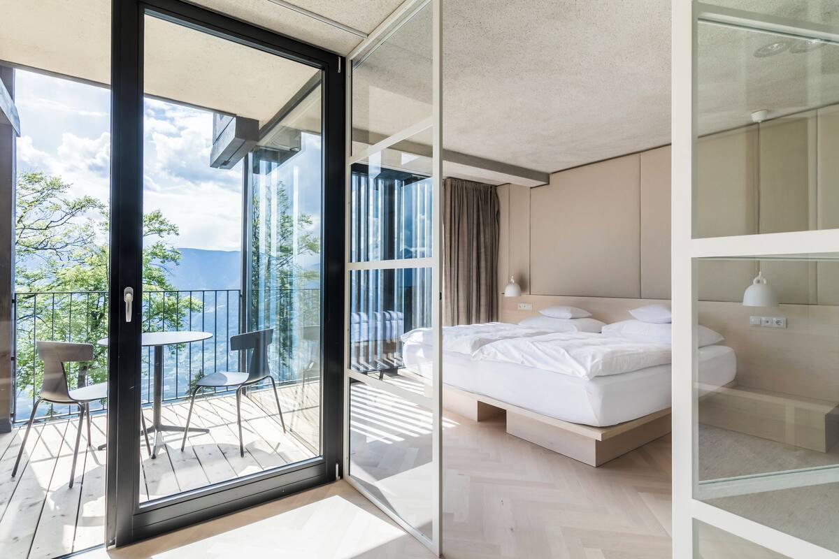 Ein modernes Hotelzimmer mit Balkon, einem Bett und Blick ins Freie.