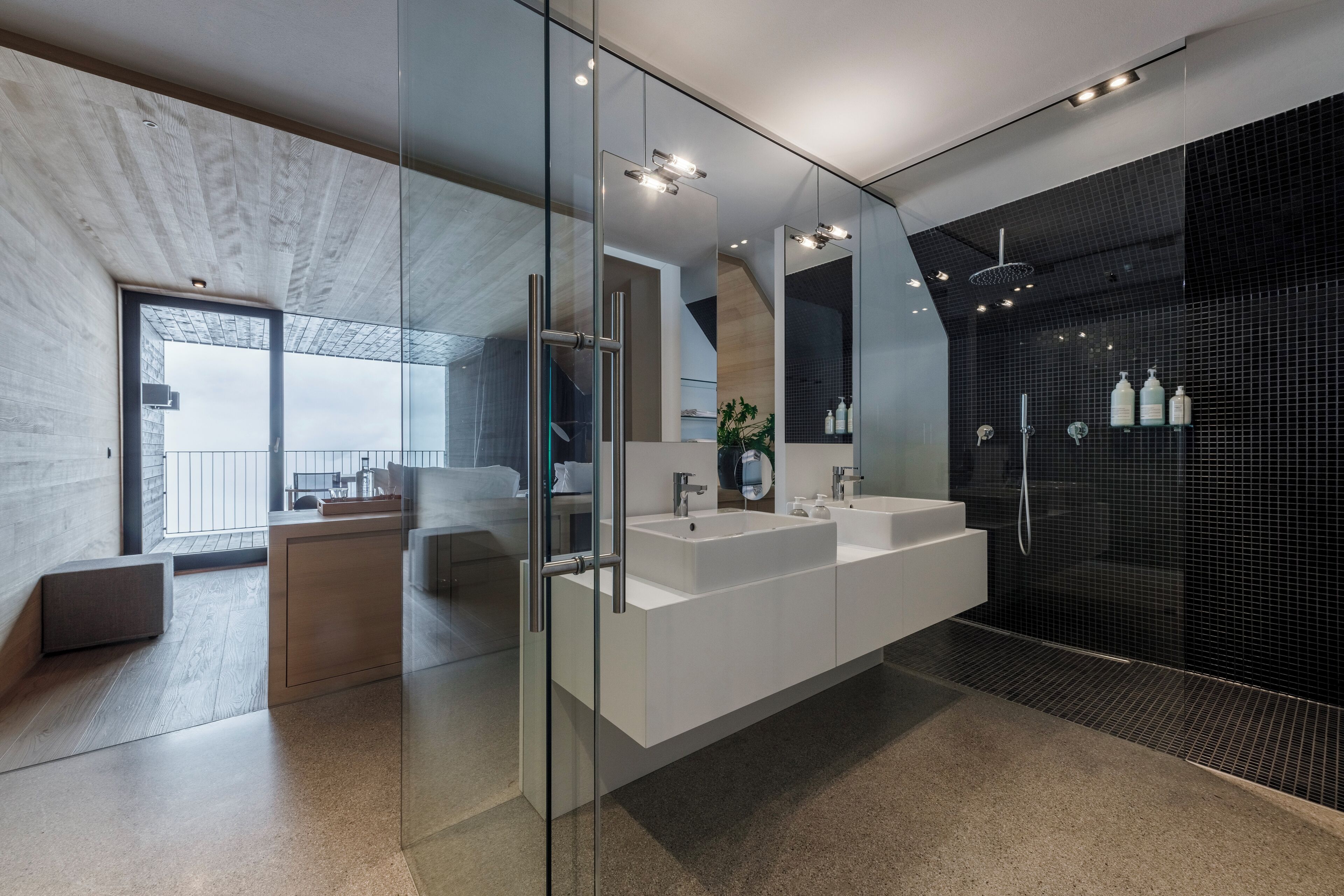 Un baño moderno con cabina de ducha de vidrio, un tocador espacioso con doble lavabo y vistas a un balcón.