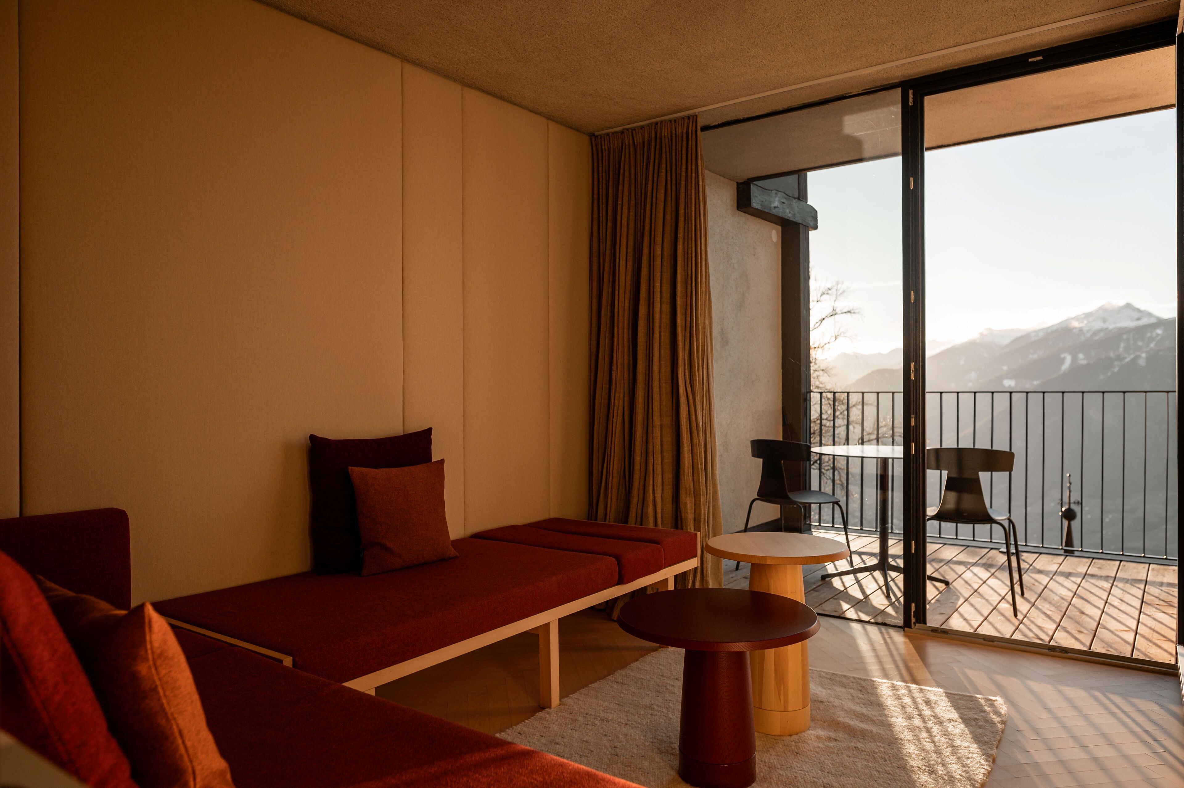Een moderne kamer met een bank, een tafeltje en uitzicht op bergen door een glazen deur.