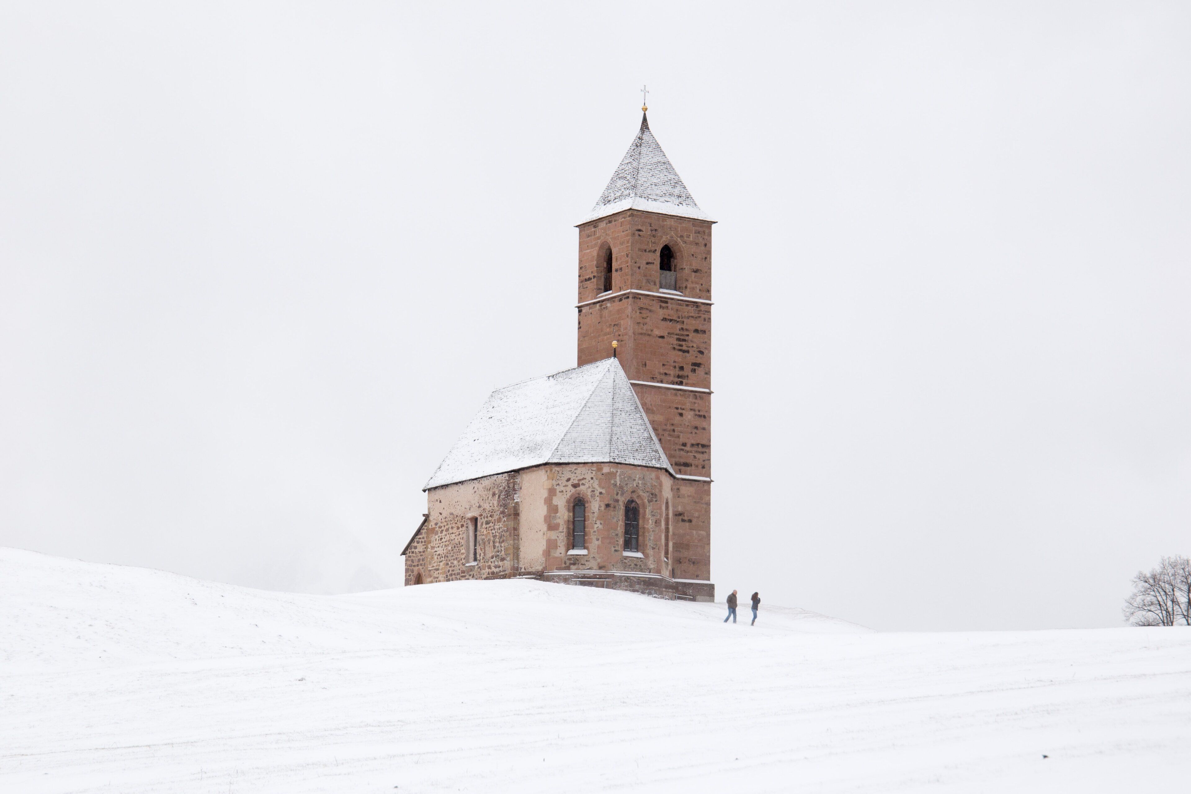 A historic church with a tall bell tower and a snow-covered roof.