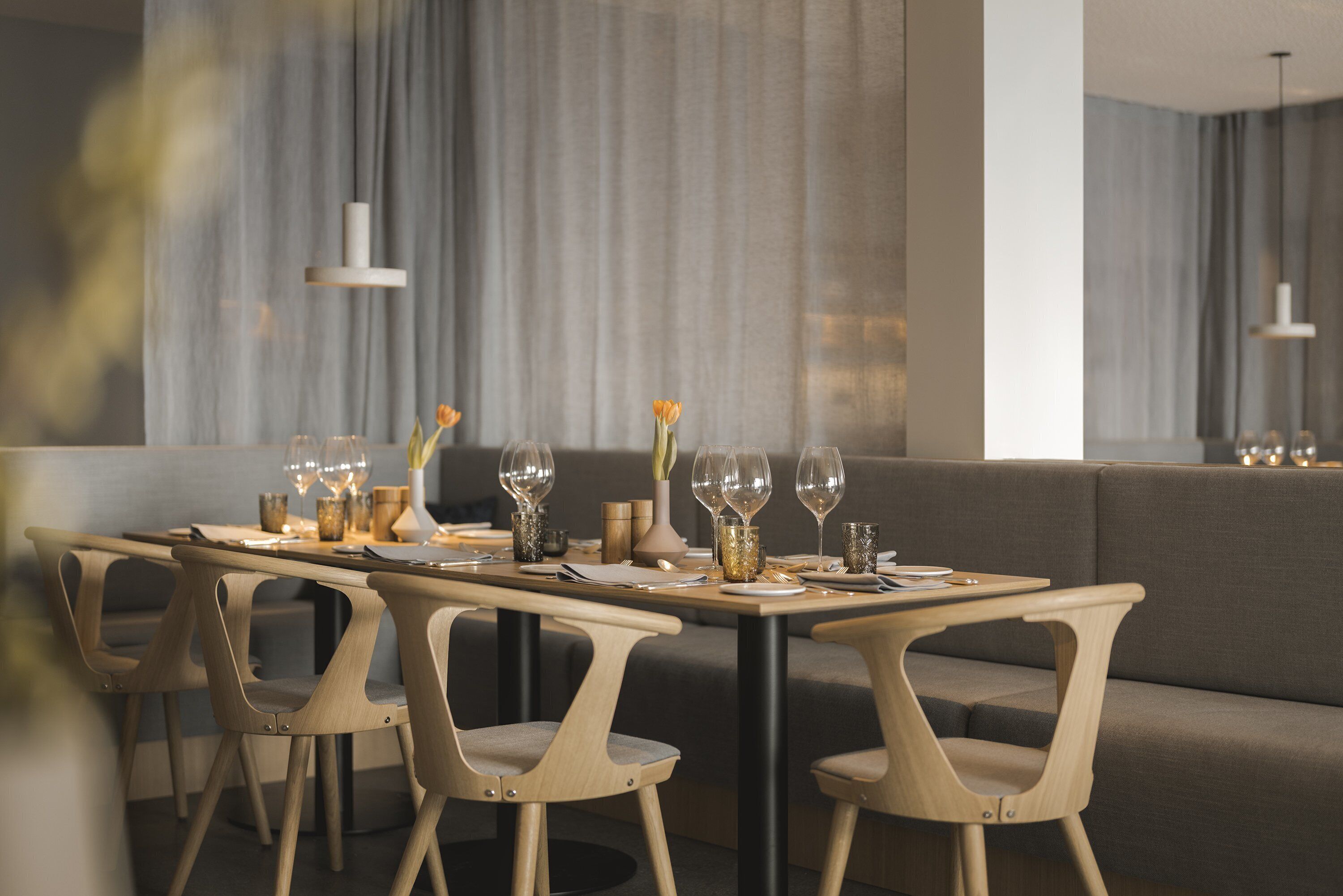 A modern dining area with a long table, four chairs, and a sofa.