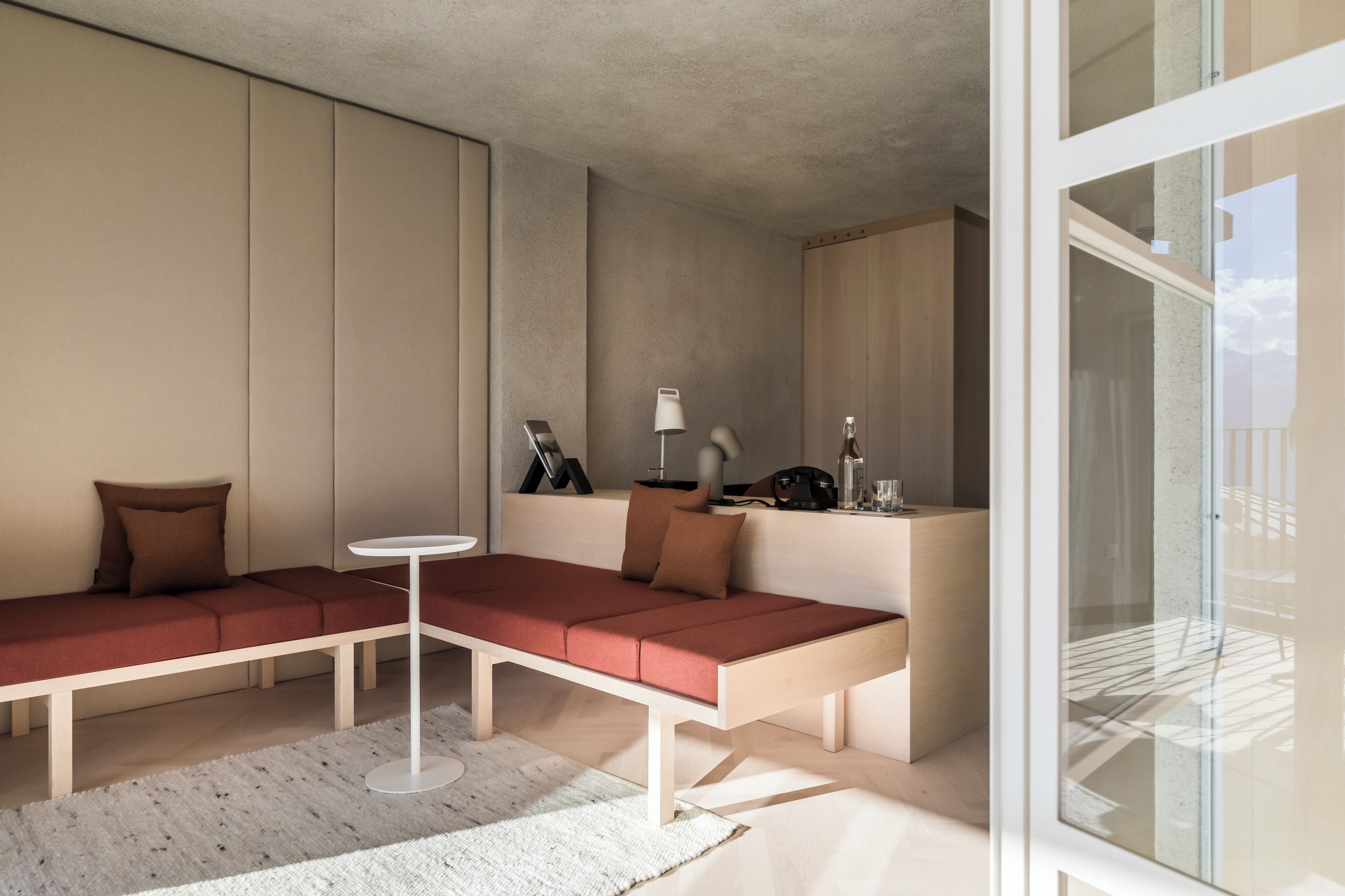 A modern living room with a sectional sofa, a small round table, and a glass partition.