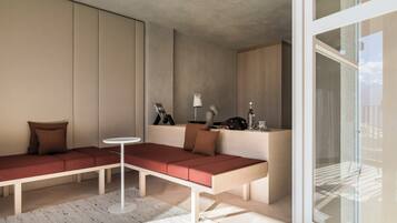 A modern living room with a sectional sofa, a small round table, and a glass partition.